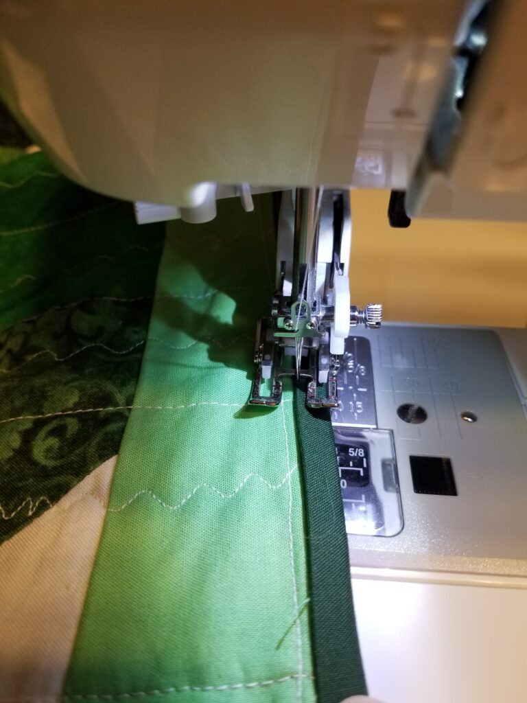 Machine sewing the binding to the front.