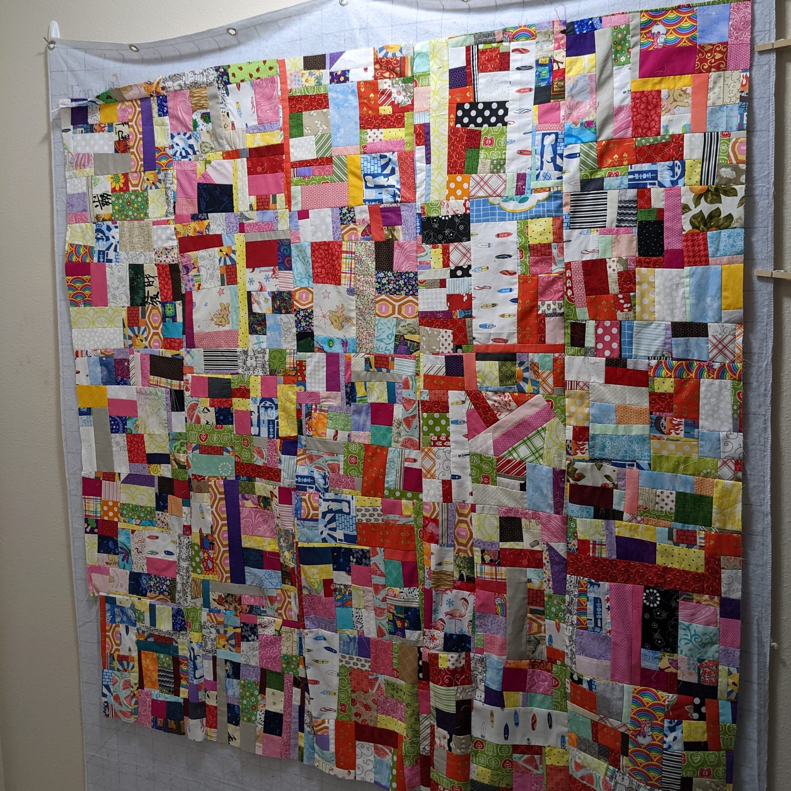 Multicolored crumb quilt top laid out on my design wall.