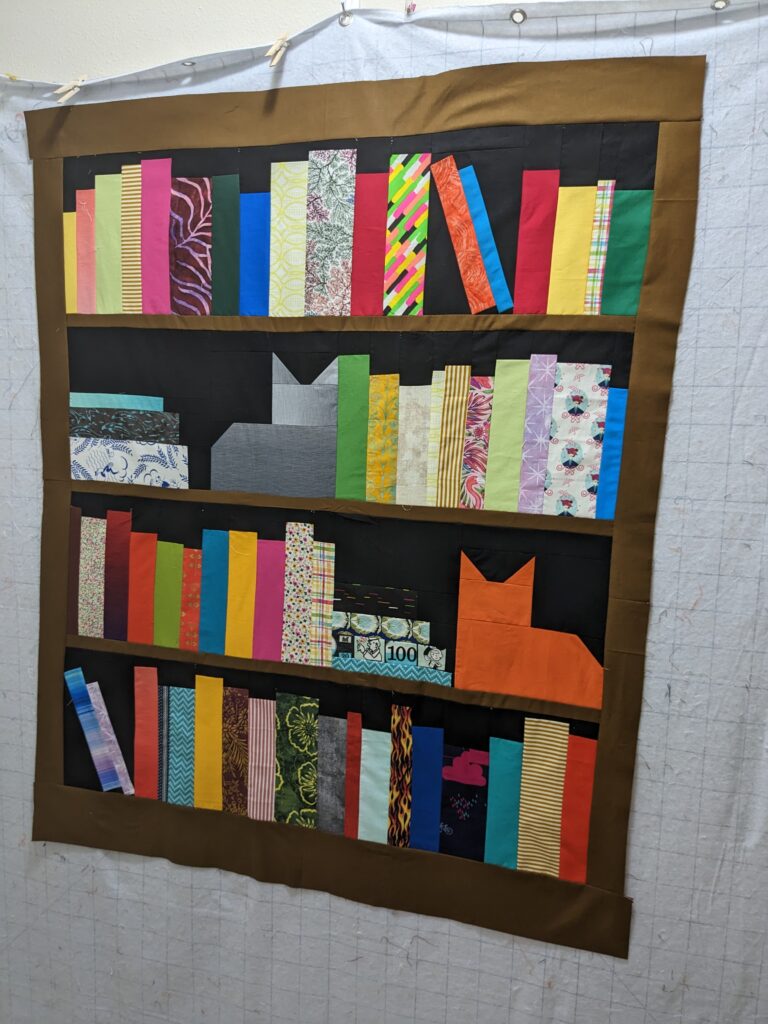 The bookcase quilt top all pieced laid out on my design wall.