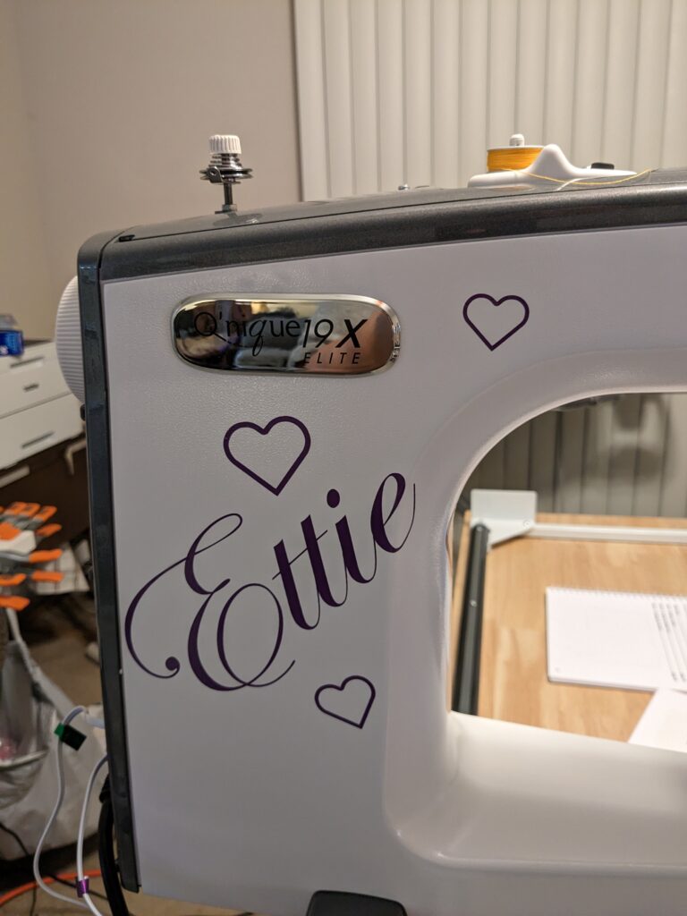 The label on my machine that says "Q'nique 19x Elite". Under that label is the vinyl I put on my machine that says "Ettie" with hearts.