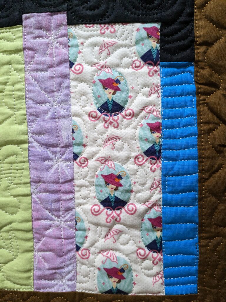 Closeup of the bookcase quilt showing where I quilted the books by tracing the fabric pattern.