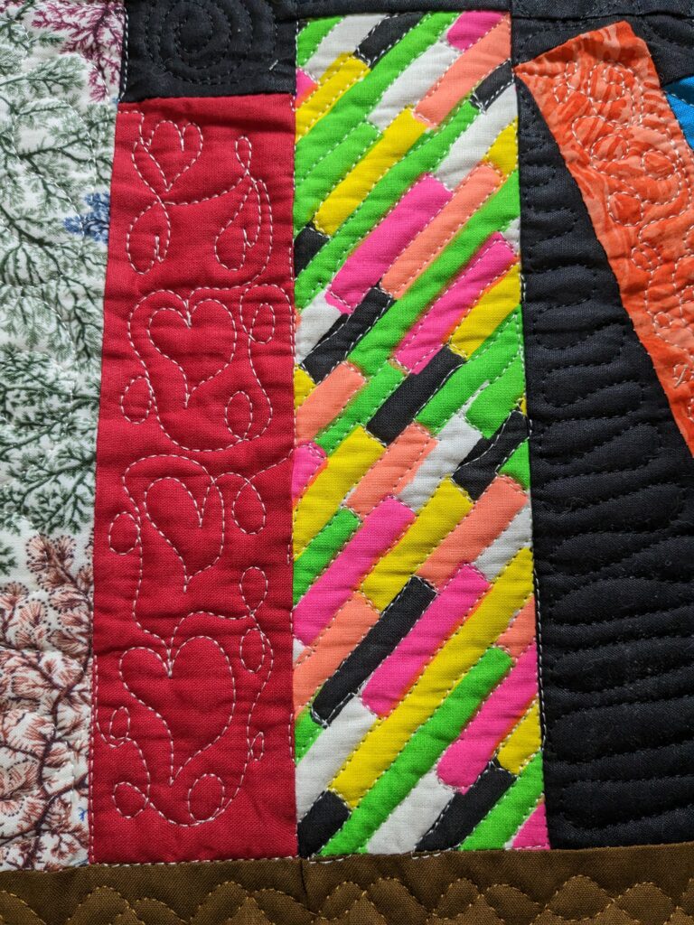 Closeup of the bookcase quilt showing a meandering heart technique and a brick technique.