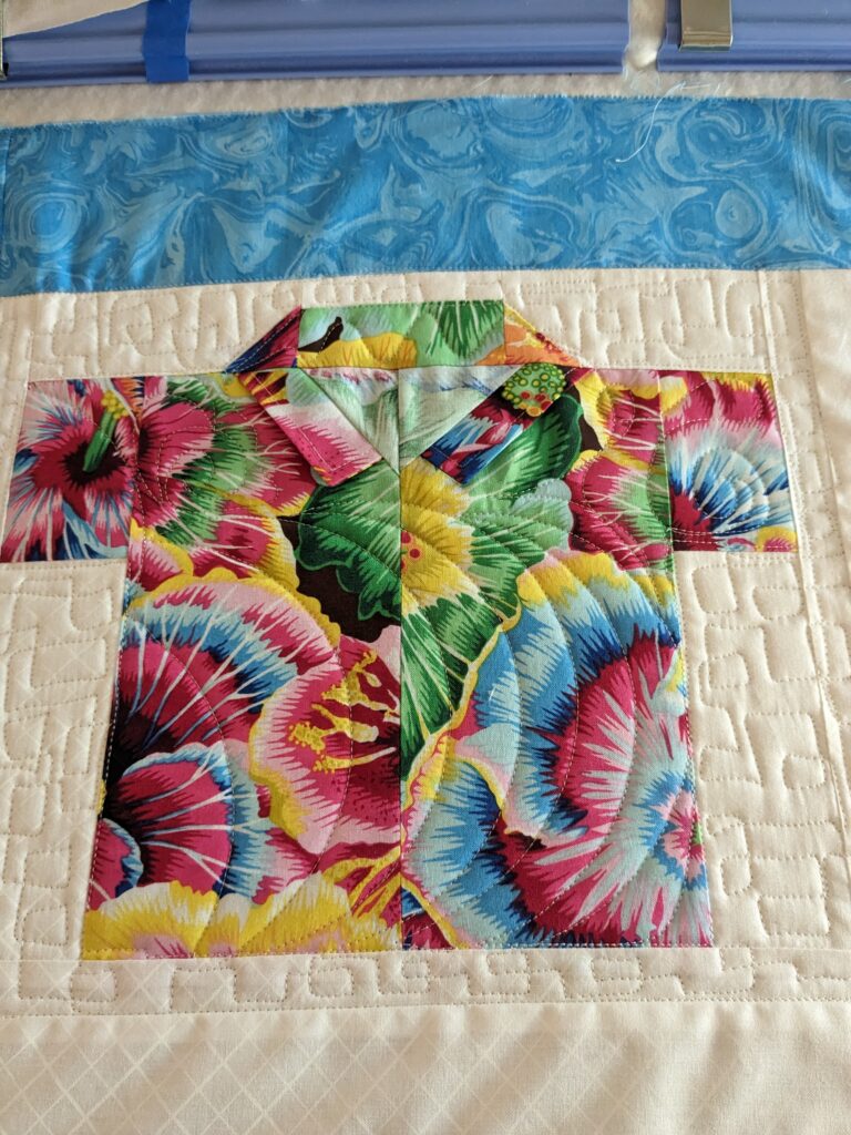 A shirt block with square meander quilting in the background and ruler made curves shirt.